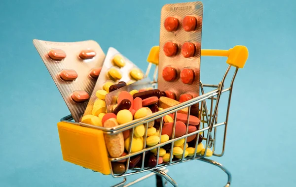 Carrelli dei supermercati pieni di capsule mediche su fondo colorato — Foto Stock