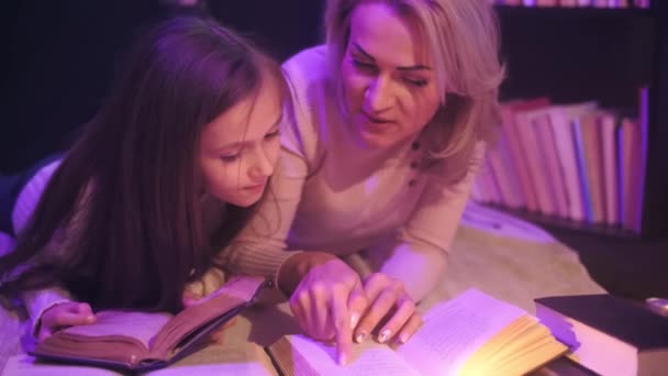 Moeder en dochter zitten samen en lezen een sprookje, gekleurde rook wervelt rond — Stockvideo