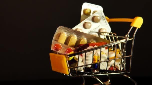 Carrello del supermercato pieno di capsule mediche su uno sfondo nero isolato — Video Stock