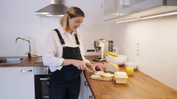 Chica embarazada haciendo sándwich en la cocina. Mamá con vientre embarazado . — Vídeos de Stock