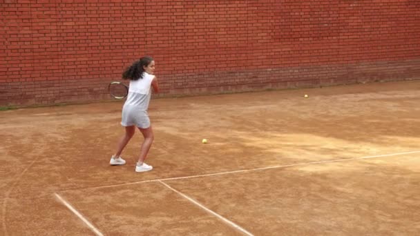 Ung flicka blockerar bollen med tennisracket under träningen — Stockvideo