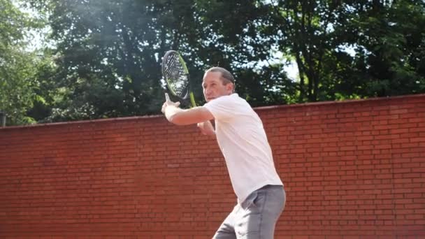 Νεαρός ελκυστικός άνδρας που παίζει τένις σε πορτοκαλί πηλό γήπεδο τένις — Αρχείο Βίντεο