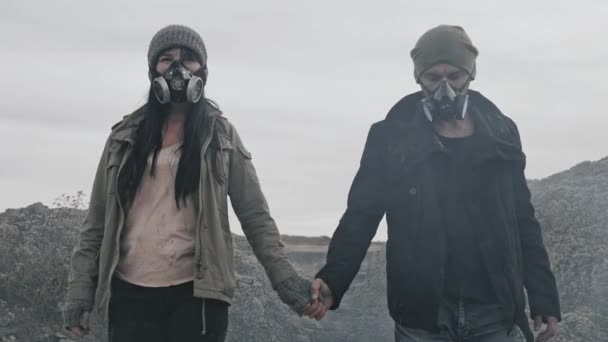 Un beau couple survivant dans un masque à gaz allant dans des nuages de fumée toxique sur un paysage forestier désolé . — Video