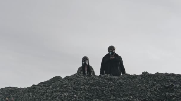 Um casal encantador sobrevivente em máscara de gás juntando as mãos durante a desolação da paisagem . — Vídeo de Stock