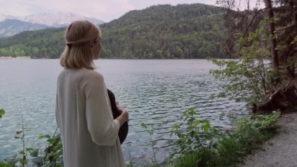 Movimiento de la cámara alrededor de la mujer embarazada de pie cerca del lago de montaña . — Vídeos de Stock