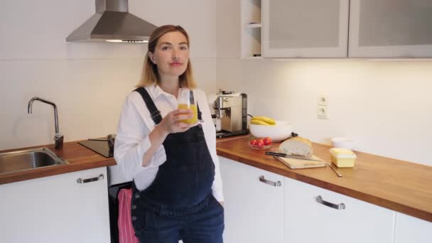 Gravid flicka dricker juice i köket. — Stockvideo