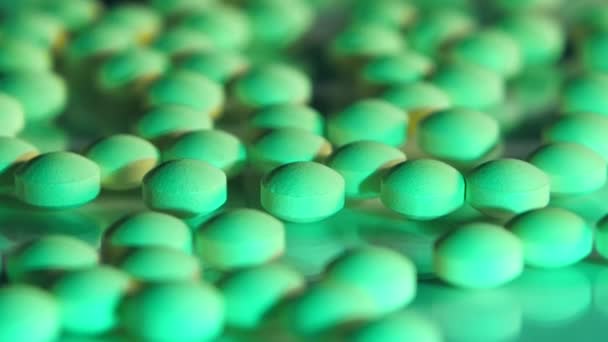 Green pills scattered on a glass table — Stock Video
