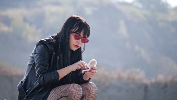 Brutal woman, crouching, drunk, sniffing powder from the powder box in the wasteland — Stock Video