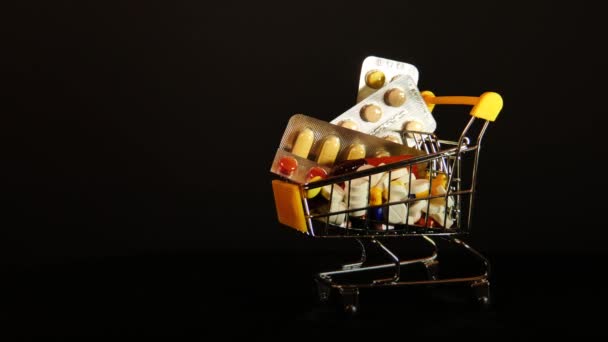 Supermarket trolley filled with medical capsules on an isolated black background — ストック動画