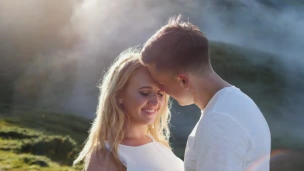 Junges verliebtes Paar auf einer Bergwiese vor dem Hintergrund von Nebel und Sonne. — Stockvideo