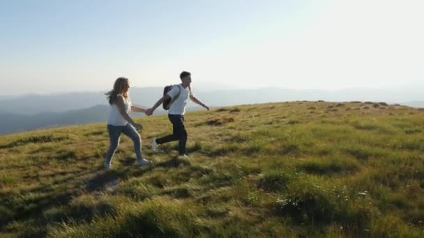 Casal pulando no prado da montanha com os braços levantados estendidos . — Vídeo de Stock