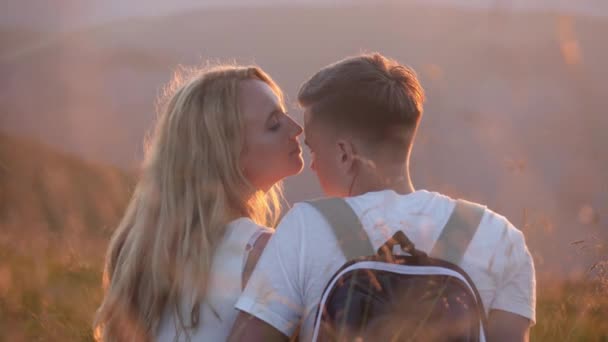 Casal amoroso sentado em um prado da montanha e desfruta da vista do pôr do sol — Vídeo de Stock