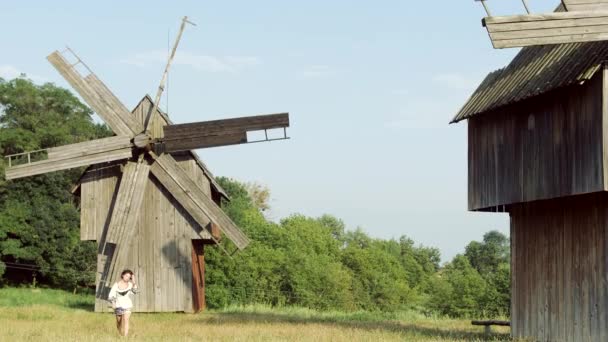 The beautiful ukrainian girl running on the background of an old mills. — Stock Video