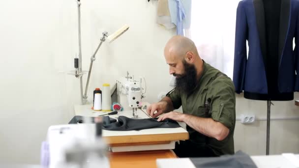 Schneider arbeitet in seinem Atelier am Tisch an einer Nähmaschine. — Stockvideo