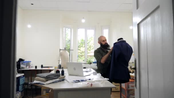 El sastre trabaja con una chaqueta sobre un maniquí en su taller . — Vídeo de stock