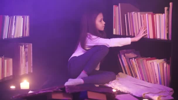 Una chica está revisando los libros en los estantes de la biblioteca, el humo mágico está dando vueltas. — Vídeos de Stock