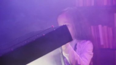 Kız sihirli bir sandık açıyor ve ışık ve renkli duman çıkıyor.