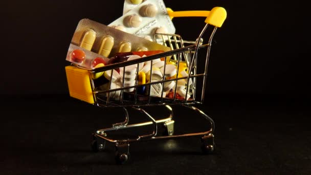 Wózek supermarketowy wypełniony kapsułkami medycznymi na odizolowanym czarnym tle — Wideo stockowe