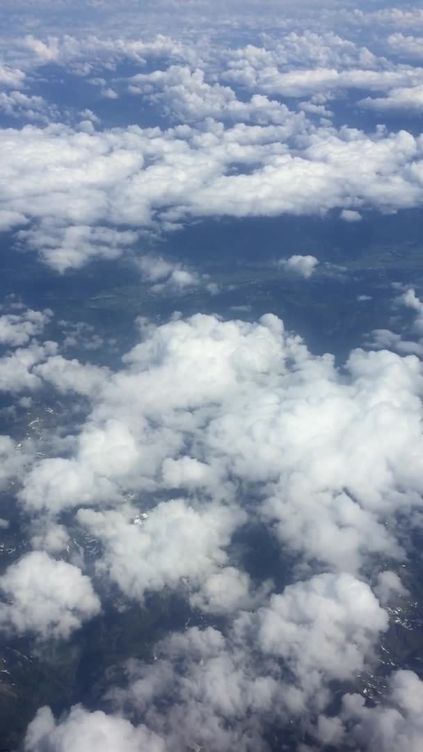 Vidéo verticale. Vue sur les montagnes depuis l'avion. Survoler un ciel et des nuages magnifiques .