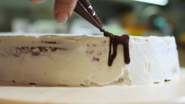 Крупный план приготовления торта на кухне, посыпать его шоколадной глазурью . — стоковое видео