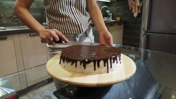 Primer plano de las manos de la mujer preparando un pastel, vertiendo el glaseado de chocolate en él . — Vídeo de stock