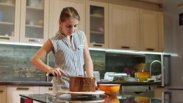 Femme mettant une crème au chocolat sur un gâteau éponge à la main à l'aide d'un couteau . — Video