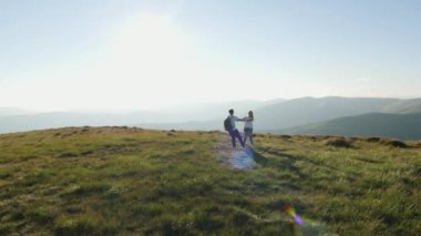 Romantik çift el ele tutuşup çayırda dönüyorlar..