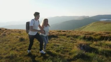 Dağdaki çayırda kolları açık atlayan bir çift..