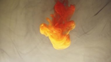 Alttan renkli gökkuşağı boyası damlıyor ve suya karışıyor. Yakın plan..