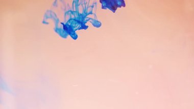 Alttan renkli gökkuşağı boyası damlıyor ve suya karışıyor. Yakın plan..