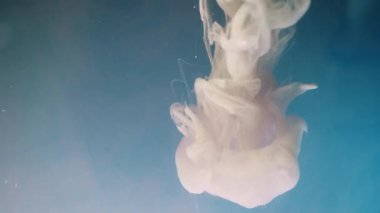 Alttan renkli gökkuşağı boyası damlıyor ve suya karışıyor. Yakın plan..