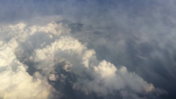 Boven de wolken bij zonsondergang Vliegen over de wolken. Zicht vanuit het vliegtuigraam op de blauwe lucht en witte wolken. Vliegen over prachtige lucht en wolken. — Stockvideo