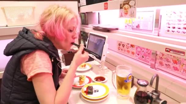 Kvinnan äter på Genki Sushi — Stockvideo