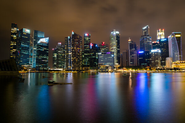 View of Singapore skyline taken from Marina bay at night with reflection in water