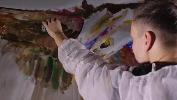Umělec kreslí orla na zeď. Řemeslník dekoratér maluje obrázek akrylovou barvou oleje. Malíř malíř oblečený v plášti.