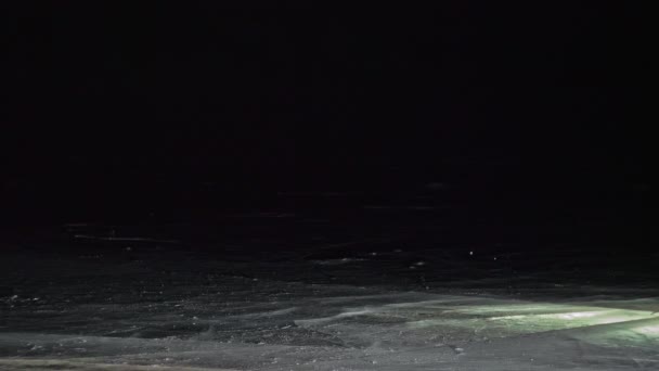 Mladý milující pár bruslí v noci na kluzišti. Muž a žena líbat objetí se naučit bruslit. Milovat se na ledě. Led osvětlený podsvícením pod.