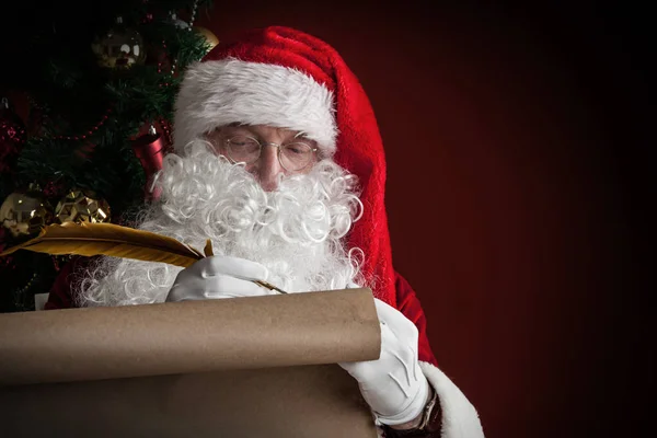 Papai Noel escrevendo em rolo de papel — Fotografia de Stock