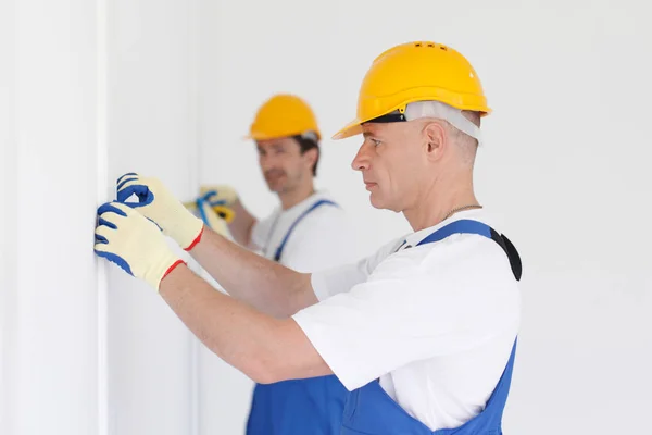 Men measuring wall with tape — Stock Photo, Image