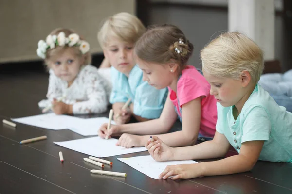 Група милих дітей малює барвистими олівцями на підлозі — стокове фото