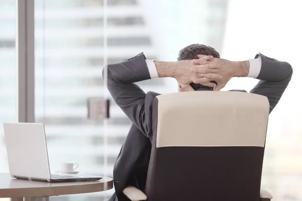 Businessman relaxes sitting in the office and looking in window — Stock Photo, Image