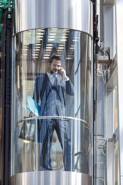 Бизнесмен в современном стеклянном лифте — стоковое фото