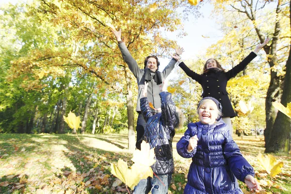 Mutlu aile sonbahar yapraklarıyla oynuyor.