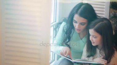 Anne ve kızı kitap okuyor.