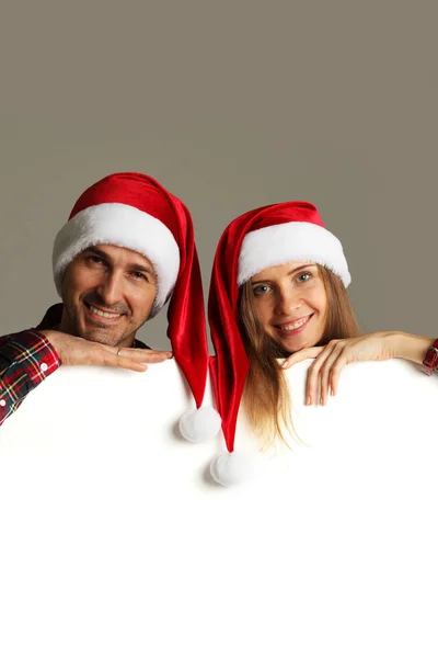 Pareja en sombreros de Santa con pancarta — Foto de Stock