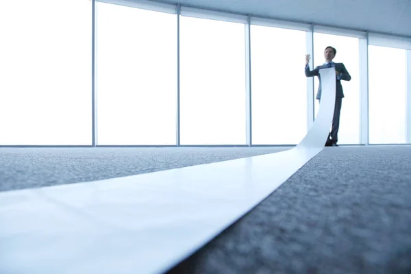 Office worker unrolling long sheet — Stock Photo, Image