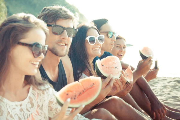 Friends eating watermelon on beach — Stock Photo, Image
