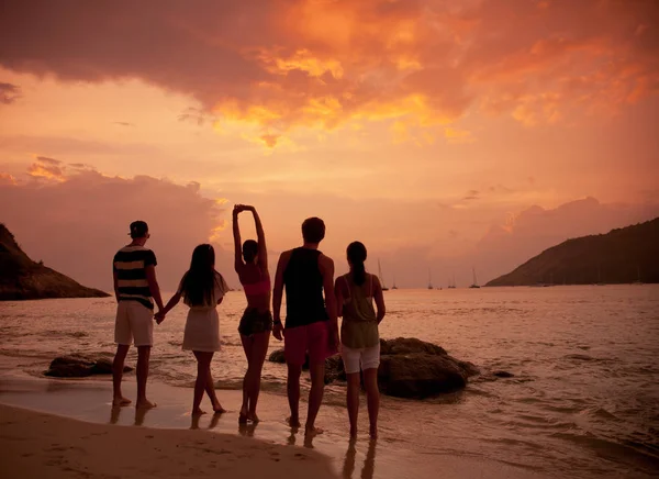 Amigos en la playa al atardecer —  Fotos de Stock