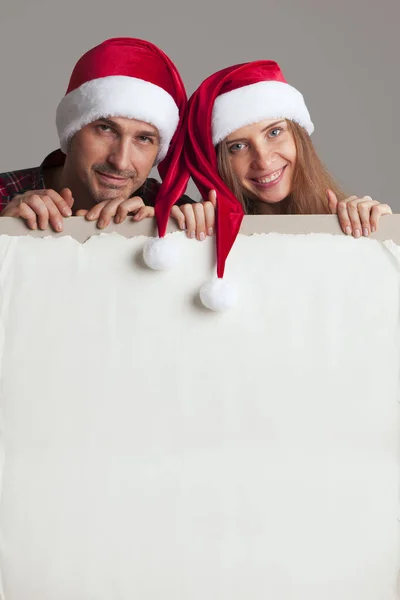 Pareja en sombreros de Santa con pancarta — Foto de Stock