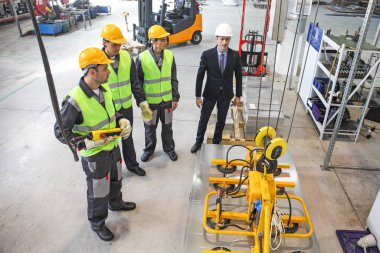 İşçiler ve elektro mıknatıslar çelik plakayı kaldırıyor