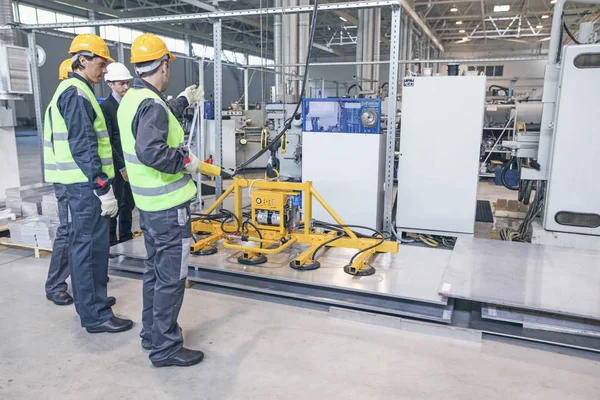 İşçiler ve elektro mıknatıslar çelik plakayı kaldırıyor